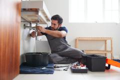male-plumber-working-to-fix-leaking-sink-in-home-bathroom